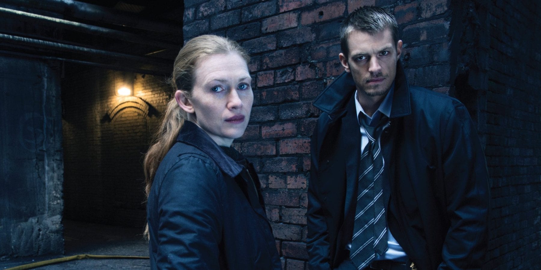 Sarah Linden (Mireille Enos) and Stephen Holder (Joel Kinnaman) look on in AMC's The Killing