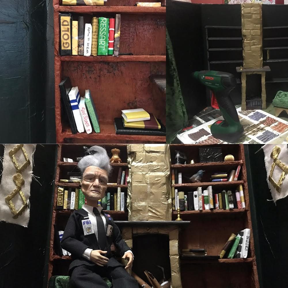 Doll of David Lynch sitting in a room of books 