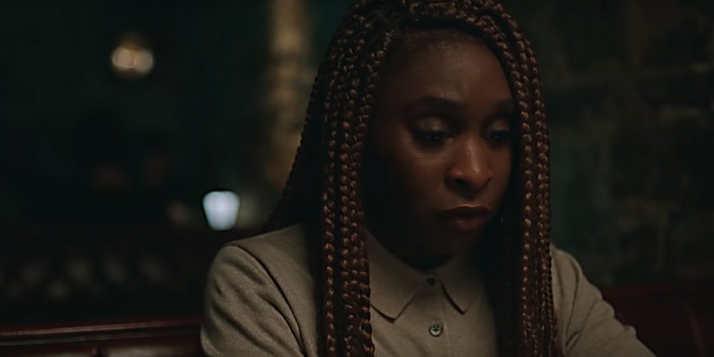 Holly Gibney sits at a table, looking down, face full of nervous emotion