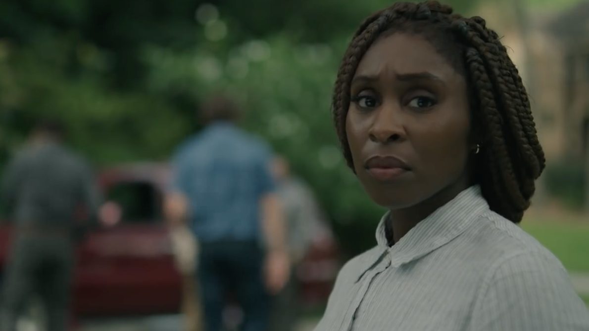 Holly stares into the distance with a group of people behind her in the background