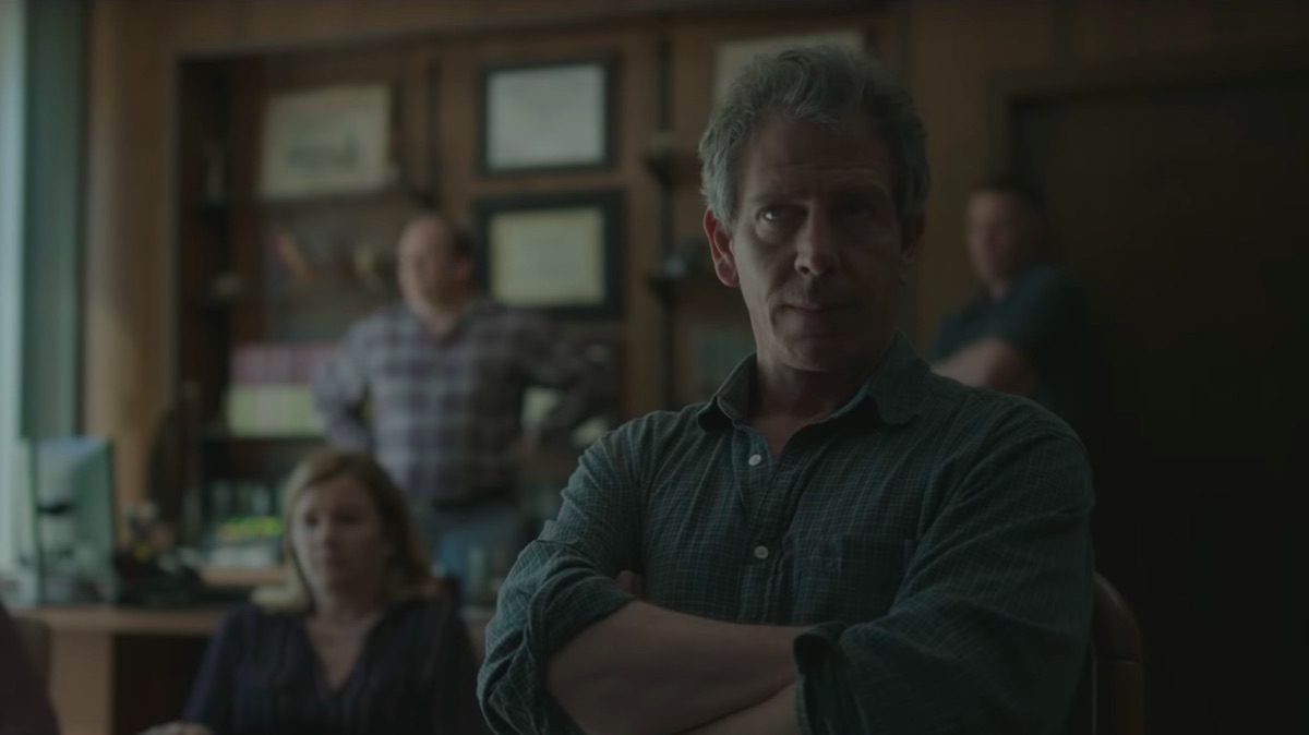 Ralphs stares ahead with his arms crossed