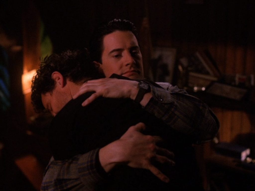 Cooper gives Harry a big hug, a destroyed Bookhouse in the background